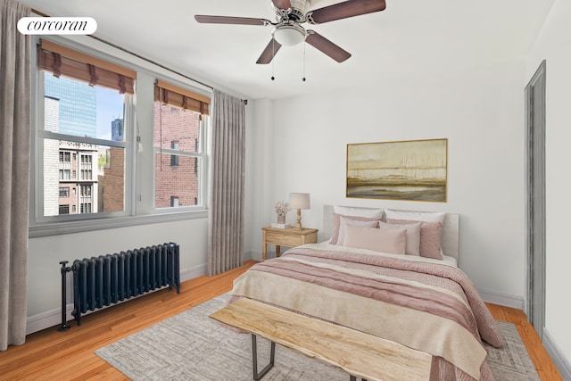 bedroom with light hardwood / wood-style floors, ceiling fan, and radiator