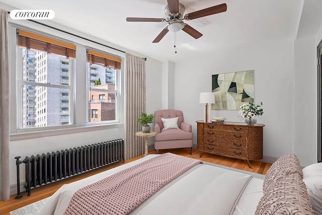 bedroom with radiator heating unit, ceiling fan, and light wood-type flooring