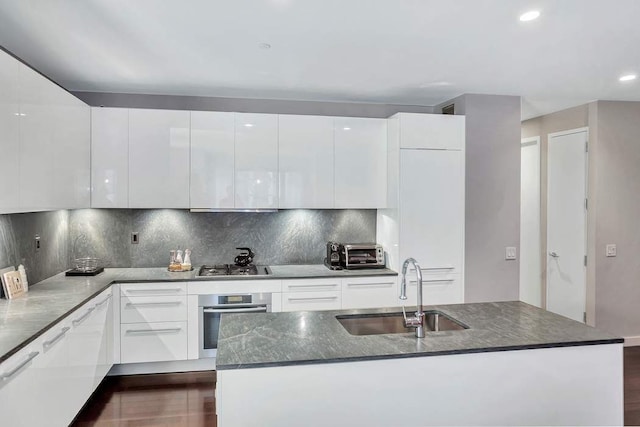 kitchen featuring backsplash, sink, dark hardwood / wood-style floors, stainless steel appliances, and white cabinets