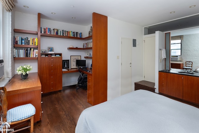 bedroom with built in desk and dark wood-type flooring