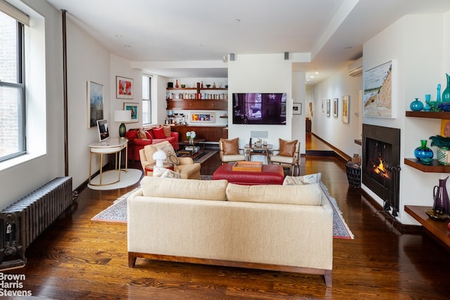 living room featuring dark hardwood / wood-style flooring, a wall unit AC, and radiator