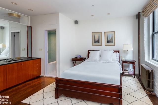 bedroom with sink, radiator, and light hardwood / wood-style flooring