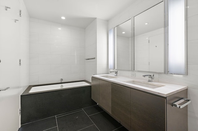 bathroom featuring vanity, a relaxing tiled tub, and tile patterned floors