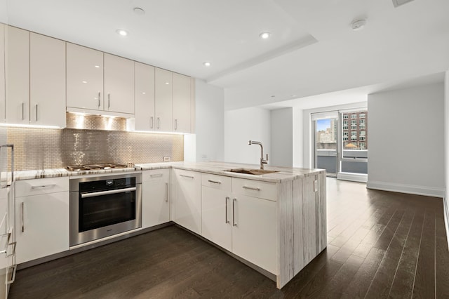 kitchen featuring kitchen peninsula, white cabinetry, stainless steel appliances, and dark wood-type flooring