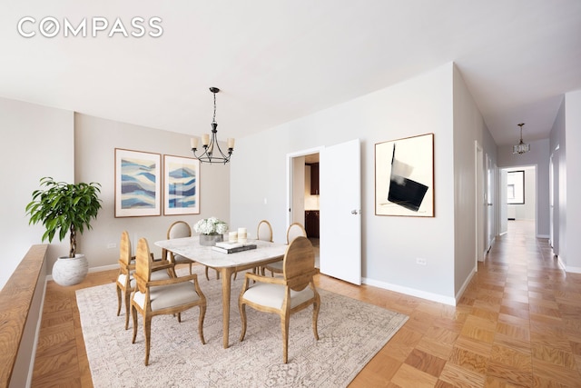 dining space featuring light parquet floors and an inviting chandelier