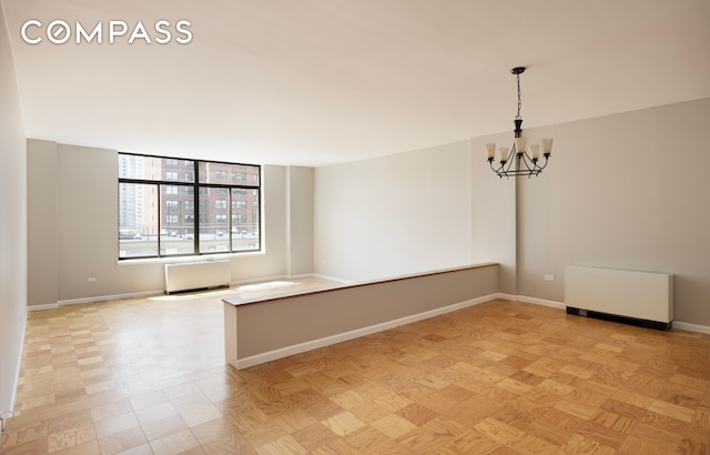 spare room with light parquet floors and a chandelier