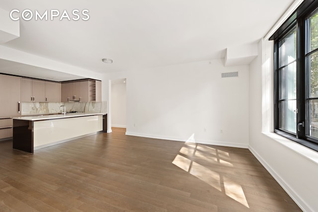 unfurnished living room with sink and dark wood-type flooring