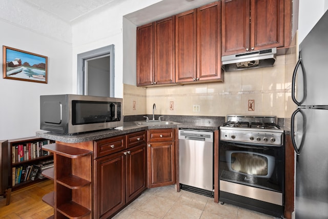 kitchen with light tile patterned floors, sink, tasteful backsplash, stainless steel appliances, and dark stone countertops