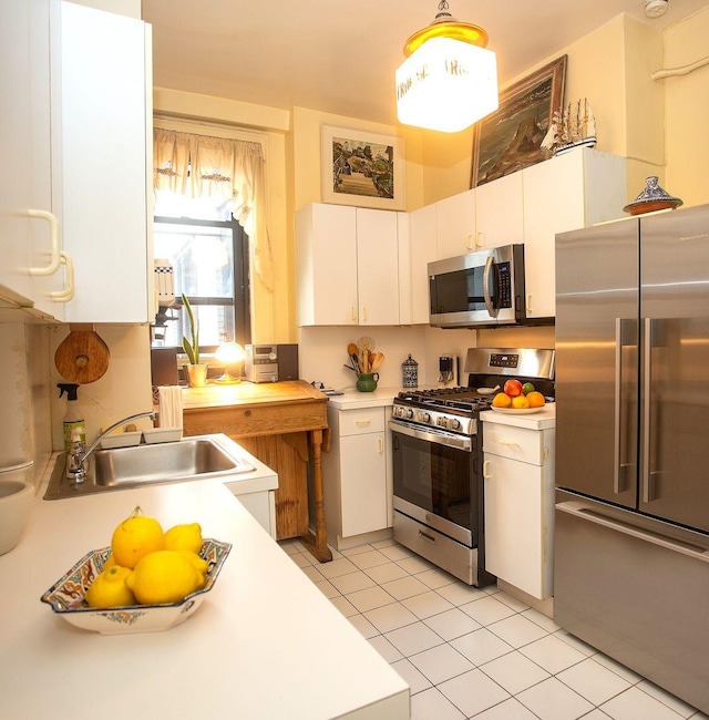 kitchen with white cabinetry, sink, hanging light fixtures, stainless steel appliances, and light tile patterned flooring