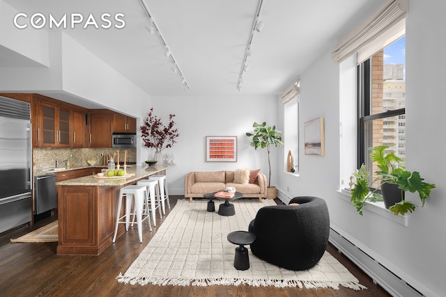 living room with dark hardwood / wood-style flooring, track lighting, and a baseboard heating unit