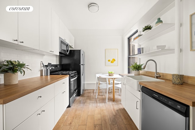 kitchen featuring appliances with stainless steel finishes, wood counters, and white cabinetry