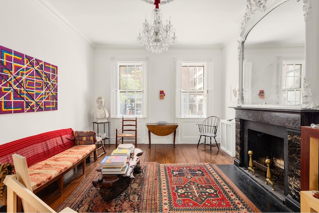 living room featuring wood-type flooring, an inviting chandelier, a high end fireplace, and ornamental molding