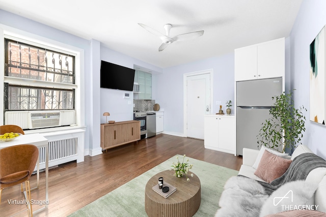 living room with radiator, dark hardwood / wood-style flooring, cooling unit, and ceiling fan