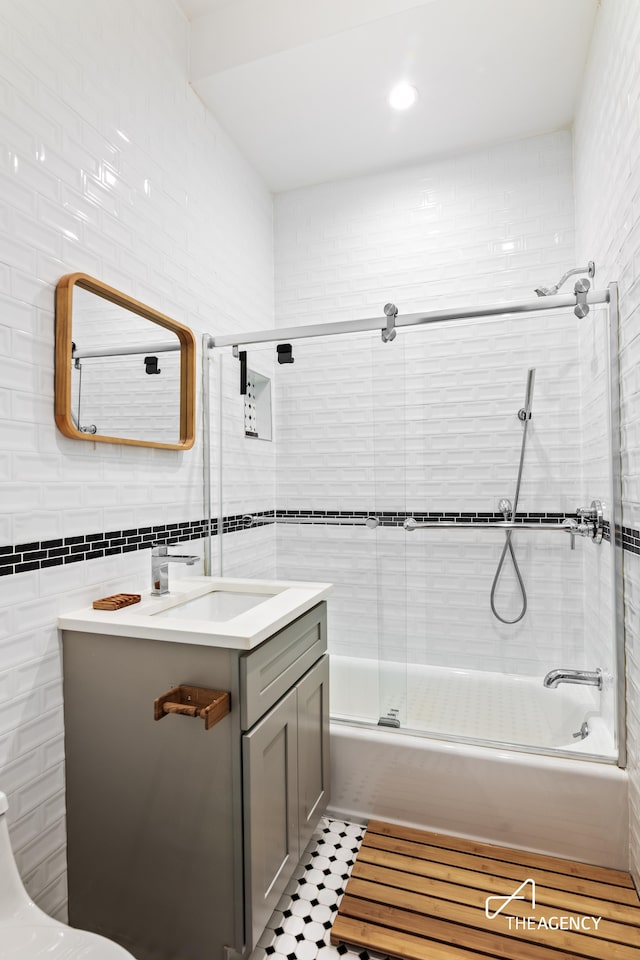 bathroom with tile patterned flooring, vanity, enclosed tub / shower combo, and tile walls