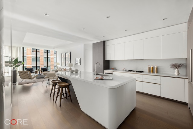 kitchen featuring an island with sink, dark hardwood / wood-style floors, and white cabinetry