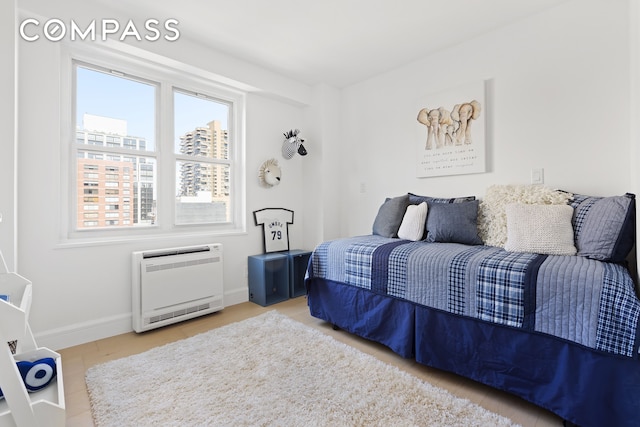 bedroom featuring heating unit and hardwood / wood-style flooring