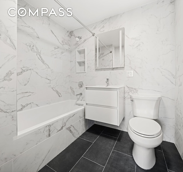 full bathroom featuring tiled shower / bath, vanity, tile walls, and toilet