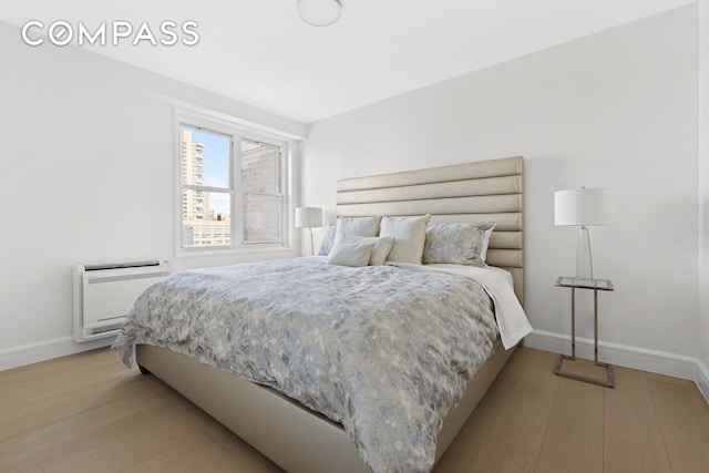 bedroom with light hardwood / wood-style flooring and heating unit