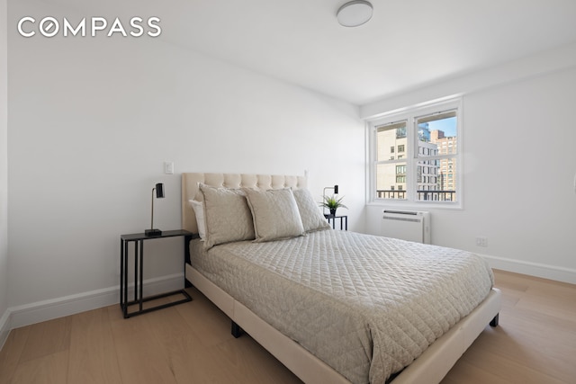 bedroom featuring hardwood / wood-style flooring and a wall mounted AC