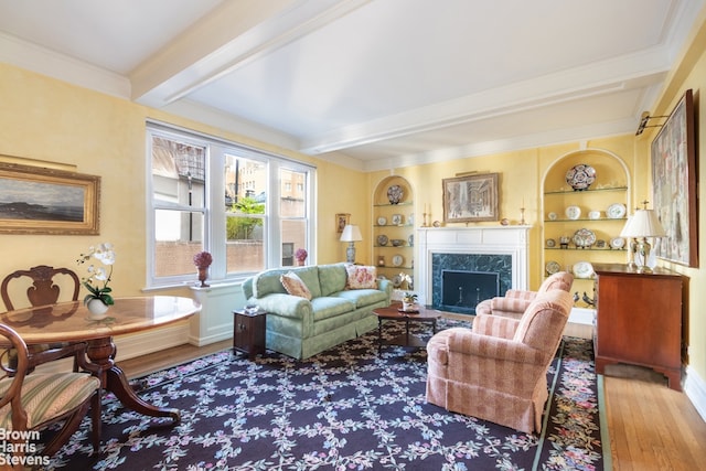 living room featuring ornamental molding, beam ceiling, wood-type flooring, and built in features