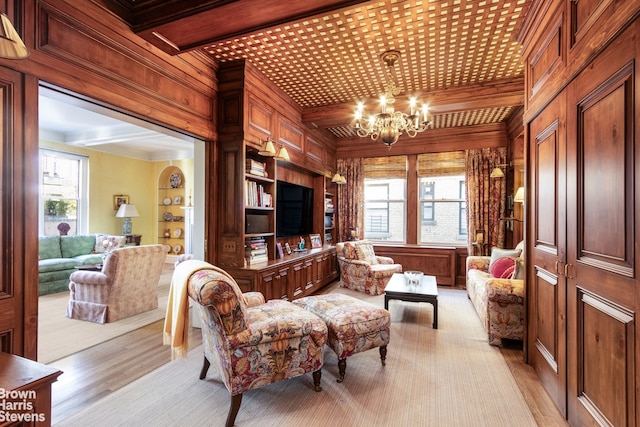 living room with an inviting chandelier, light hardwood / wood-style flooring, and wooden walls