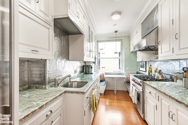 kitchen featuring white cabinets, backsplash, hanging light fixtures, and high end range