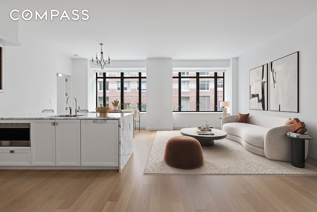 kitchen with a notable chandelier, white cabinets, light hardwood / wood-style flooring, and stainless steel oven