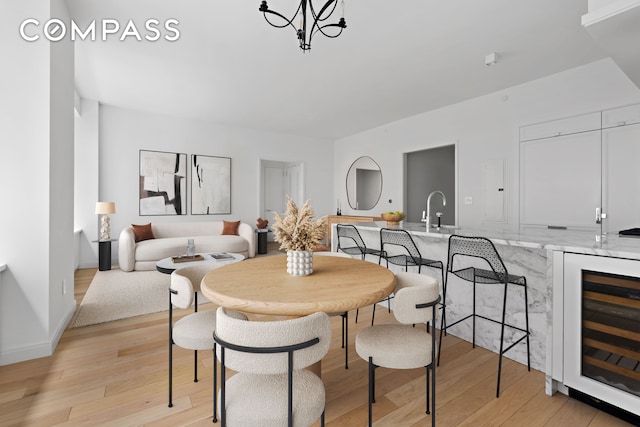 dining space with light hardwood / wood-style flooring, sink, and beverage cooler