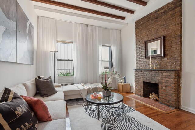 living room with a fireplace, wood-type flooring, and beam ceiling