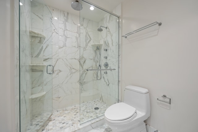 bathroom featuring toilet and a shower with shower door