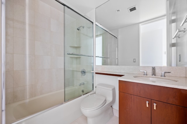 full bathroom featuring vanity, bath / shower combo with glass door, toilet, and tile patterned flooring