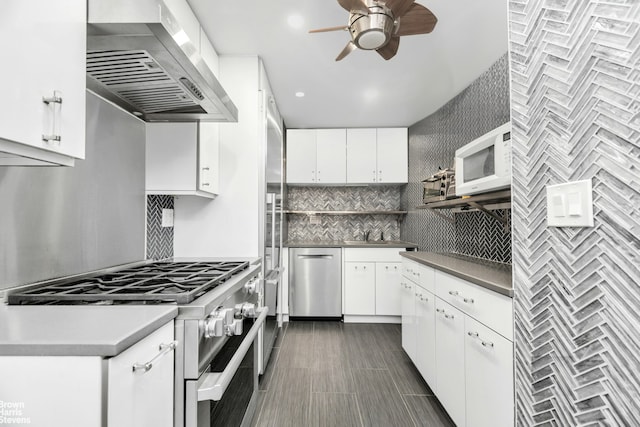 kitchen with stainless steel appliances, dark hardwood / wood-style flooring, ceiling fan, wall chimney exhaust hood, and white cabinets