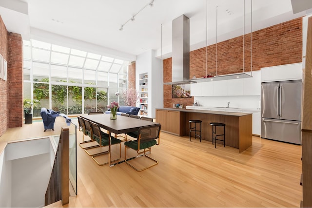 dining area with a high ceiling, sink, light hardwood / wood-style flooring, and track lighting