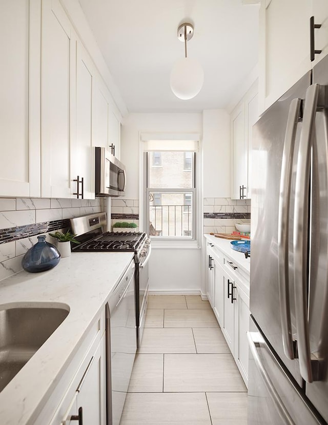 kitchen featuring light stone countertops, appliances with stainless steel finishes, white cabinetry, and tasteful backsplash