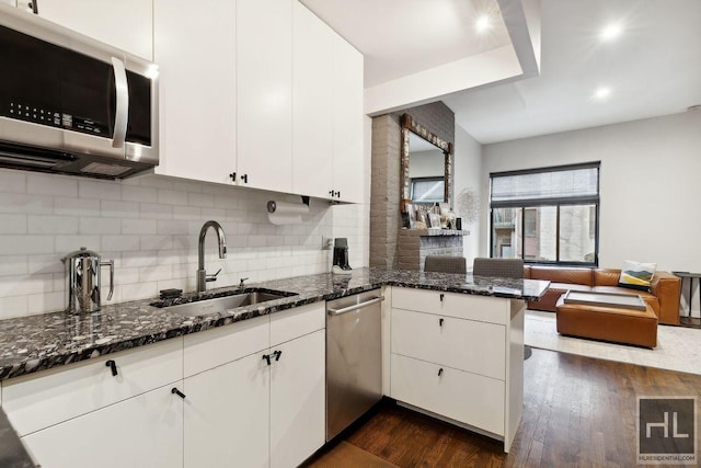 kitchen with tasteful backsplash, dark stone countertops, kitchen peninsula, white cabinets, and appliances with stainless steel finishes