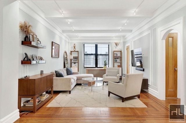 living room featuring beam ceiling, light parquet flooring, and track lighting