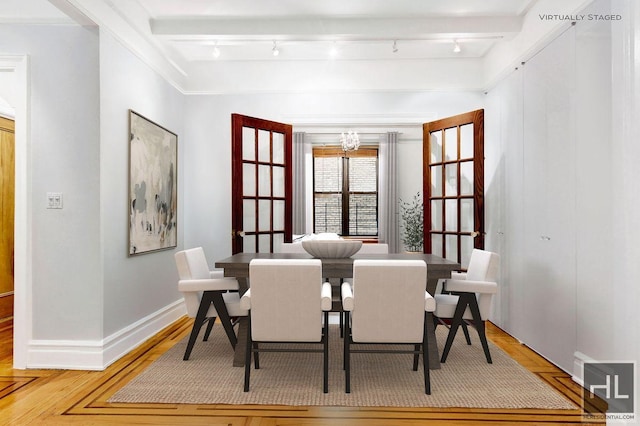 dining space with beamed ceiling, wood-type flooring, rail lighting, and a chandelier