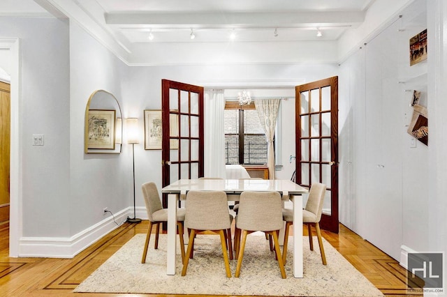 dining room featuring beam ceiling, an inviting chandelier, track lighting, and light parquet floors