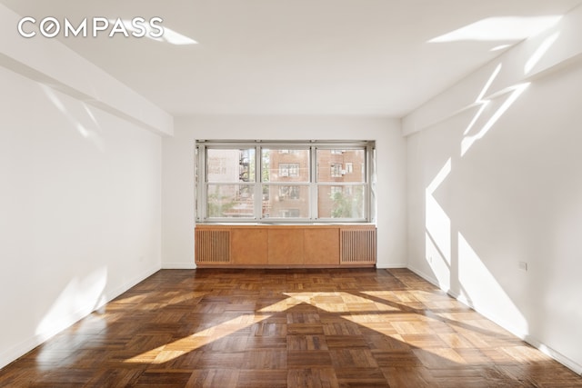 spare room featuring parquet flooring and radiator