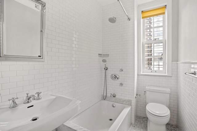 full bathroom with tile walls, toilet, sink, and tiled shower / bath