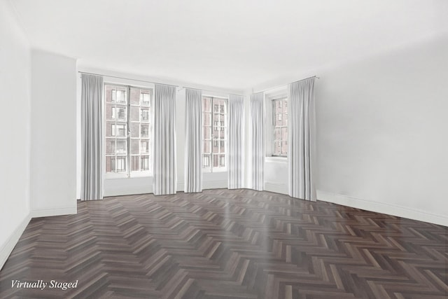 empty room with dark parquet floors and plenty of natural light