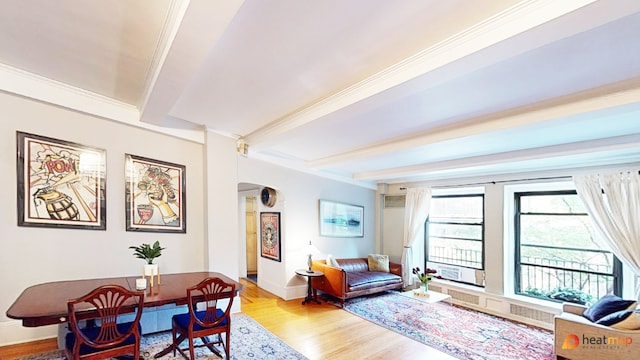 living room featuring beamed ceiling, light hardwood / wood-style flooring, and ornamental molding