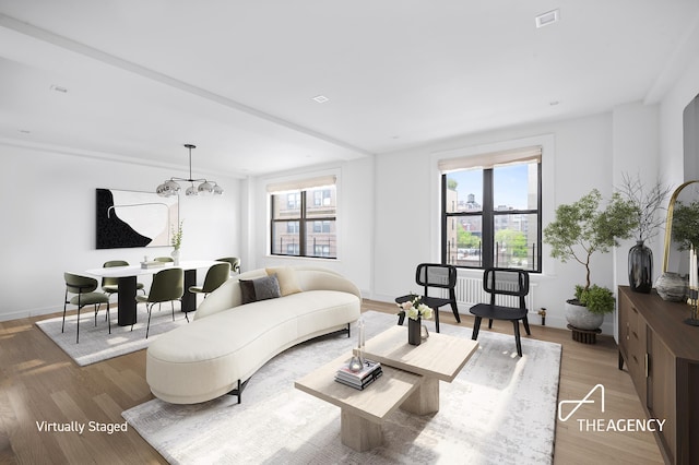 living room with a wealth of natural light, wood-type flooring, and a notable chandelier