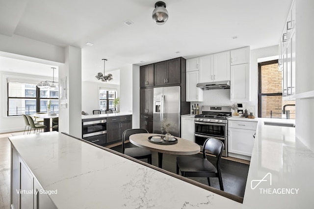 kitchen with light stone counters, white cabinetry, appliances with stainless steel finishes, decorative backsplash, and sink