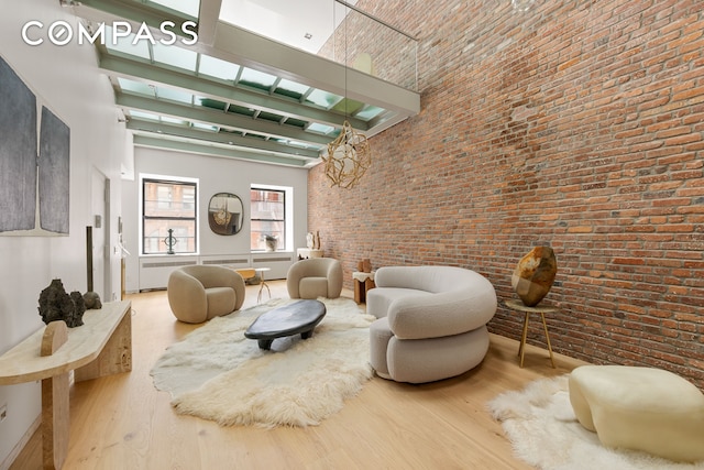 interior space with brick wall, a high ceiling, and light hardwood / wood-style floors