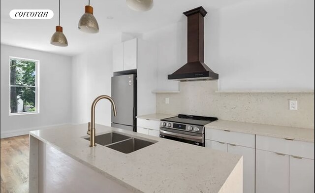 kitchen with white cabinets, hanging light fixtures, light stone countertops, wall chimney exhaust hood, and stainless steel appliances