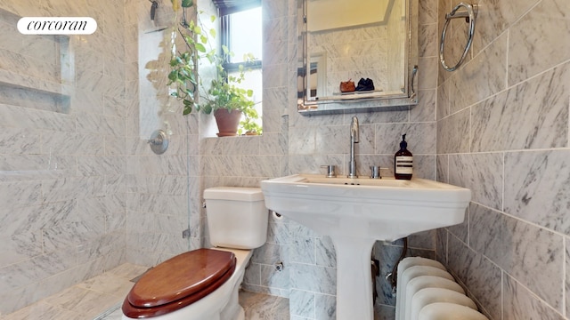 bathroom featuring tiled shower, toilet, tile walls, and radiator