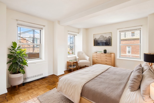 bedroom with multiple windows, parquet floors, beam ceiling, and radiator heating unit