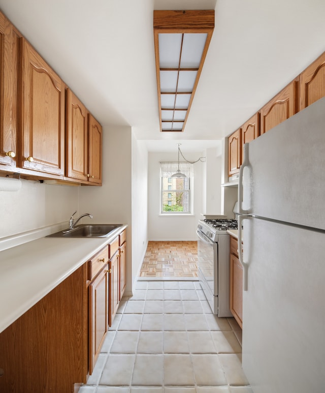 kitchen with gas range oven, sink, and white refrigerator