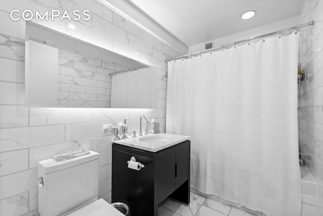 bathroom with vanity, toilet, and tile walls